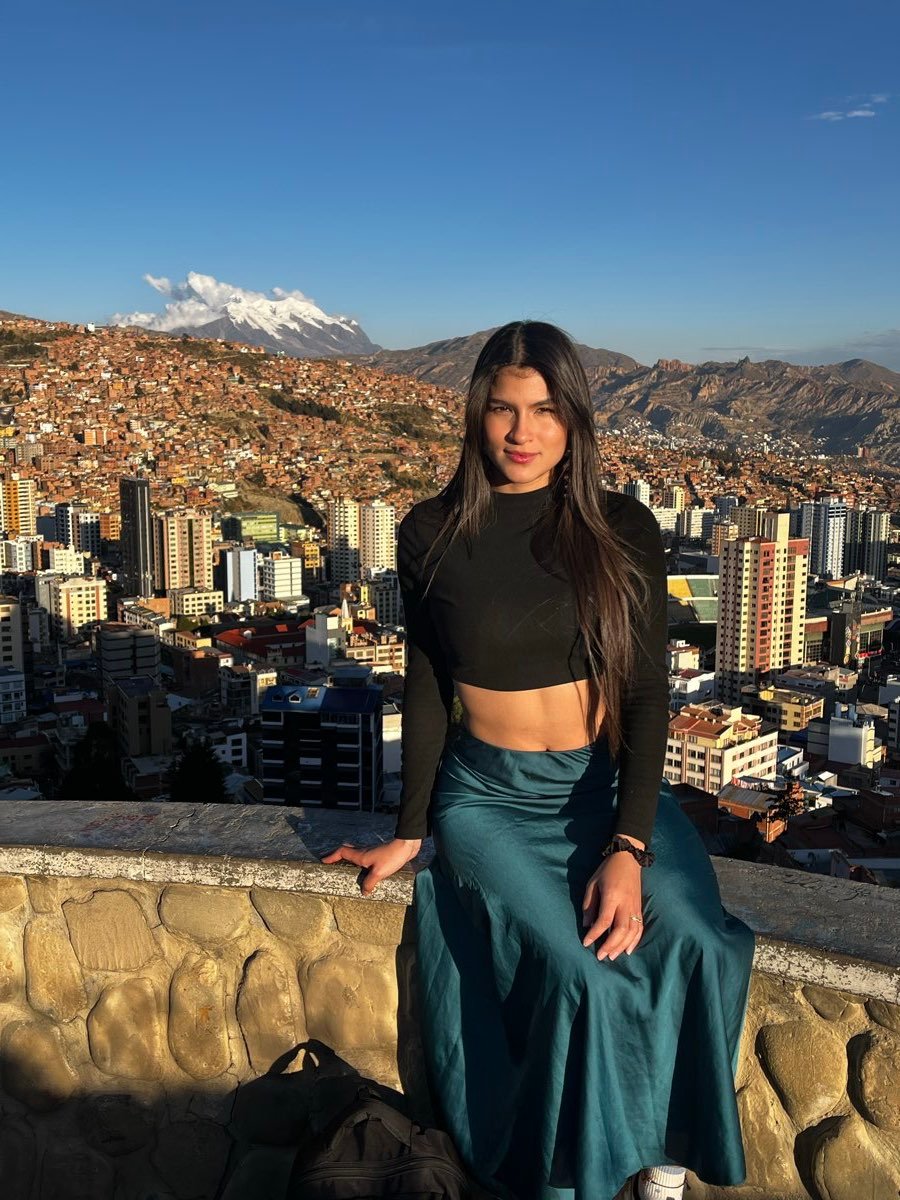 Dana sentada en un mirador, con La Paz y una montaña nevada al fondo